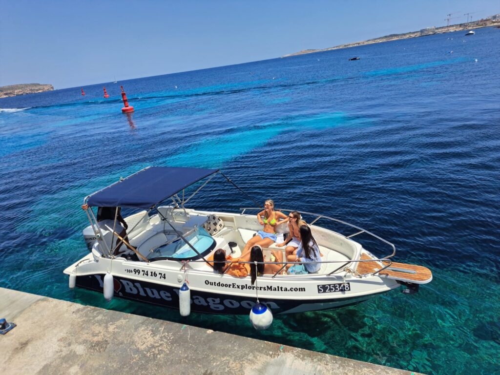 Private boat with shade anchored at the Blue Lagoon Malta, surrounded by clear blue water near Comino Island.