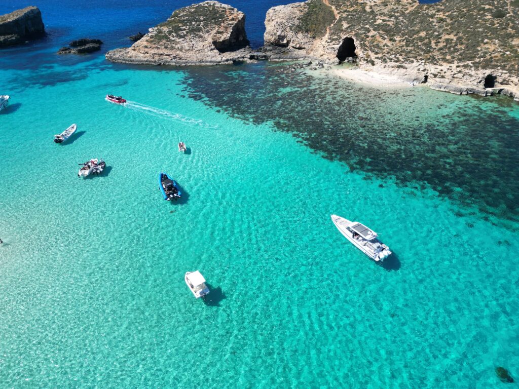 Private boat charter in the Blue Lagoon, Malta, surrounded by crystal blue waters and calm conditions ideal for swimming and relaxing.