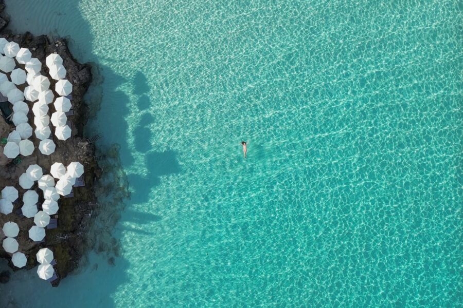 Aerial photo of Blue Lagoon Malta showing blue water, umbrellas and deckchairs from above in summer.