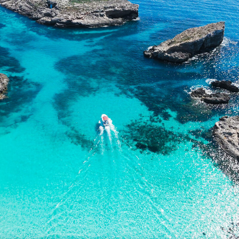 Boat passing Comino Blue Lagoon with crystal blue water, no crowds, no people, photographed early morning from a private boat.