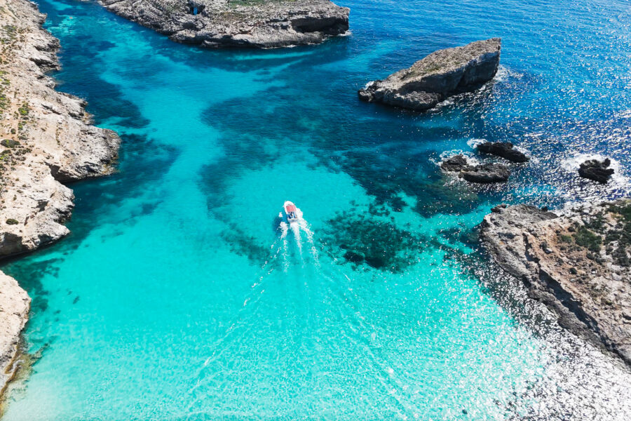 Boat passing Comino Blue Lagoon with crystal blue water, no crowds, no people, photographed early morning from a private boat.