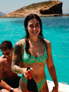 Happy couple enjoying a private boat tour in Comino with clear blue water, peaceful atmosphere, and scenic island coastline.