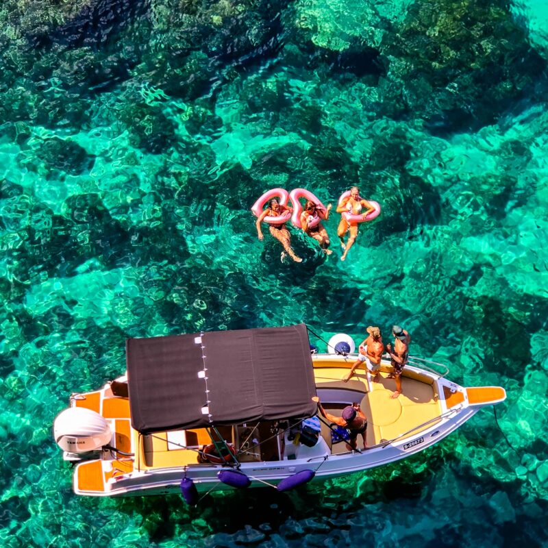 Boat in the Crystal Lagoon in Comino, Malta, with people having fun in clear blue water during a relaxed private boat tour.