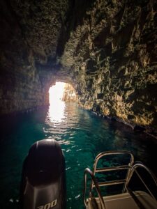 Private boat exploring a sea cave in Comino, Malta, surrounded by clear blue water during a calm and scenic boat tour experience.