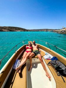 Couple enjoying a private boat at the Blue Lagoon in Malta, surrounded by calm crystal blue water during a relaxed and romantic experience.