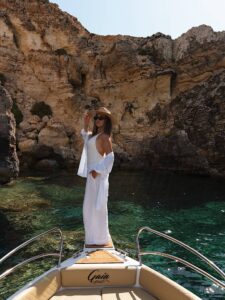 Lady on the front jumping platform of a private boat in Comino, Malta, with crystal blue water creating a picture-perfect moment.
