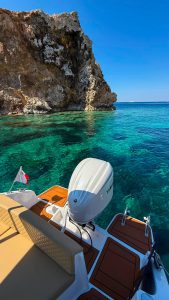 Boat anchoring at Secret Beach Comino in clear blue water