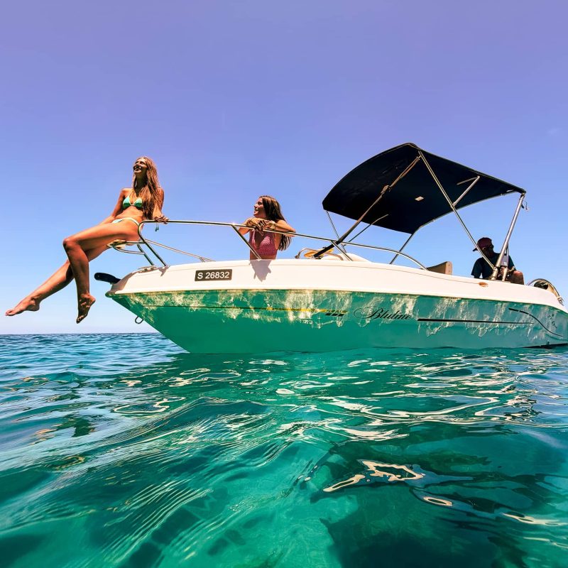 Private boat rental cruising through crystal-clear blue water near Comino’s Blue Lagoon, Malta