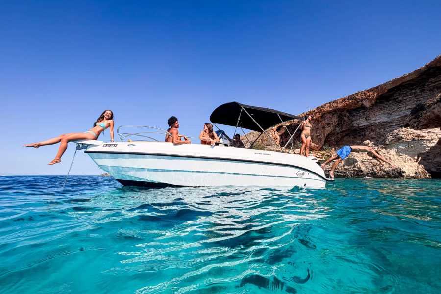 Private Gaia boat with front swimming platform anchored in crystal-clear blue water away from crowds in Comino Malta